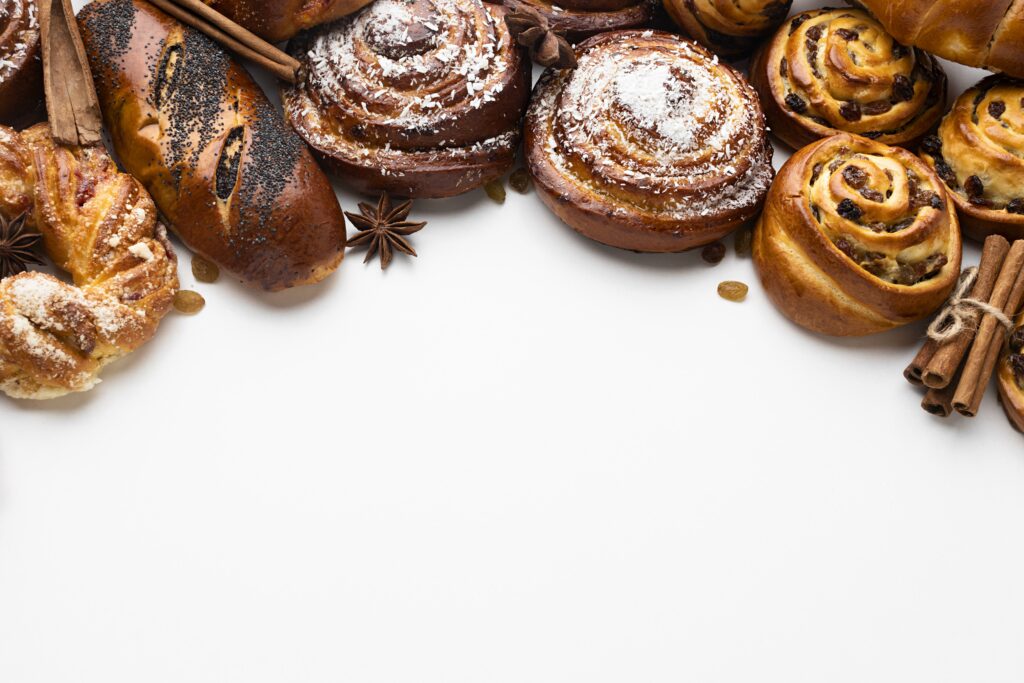 Assortiment de viennoiseries fraîches en forme de lune pour la présentation, comprenant croissants, pains au lait, pains aux raisins et brioches.